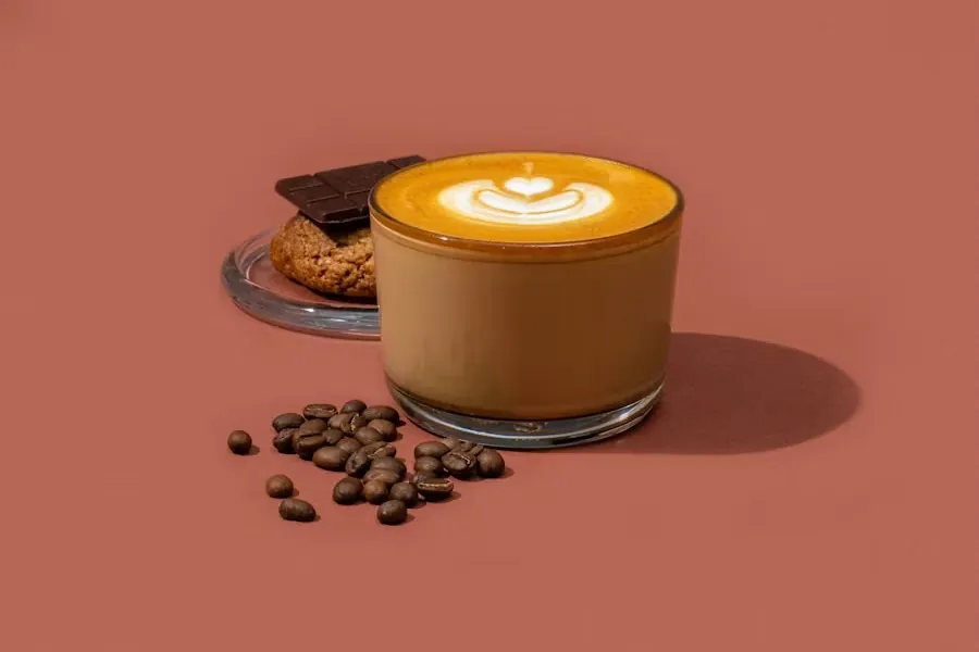 A flat white in a glass cup with coffee beans scattered beside it